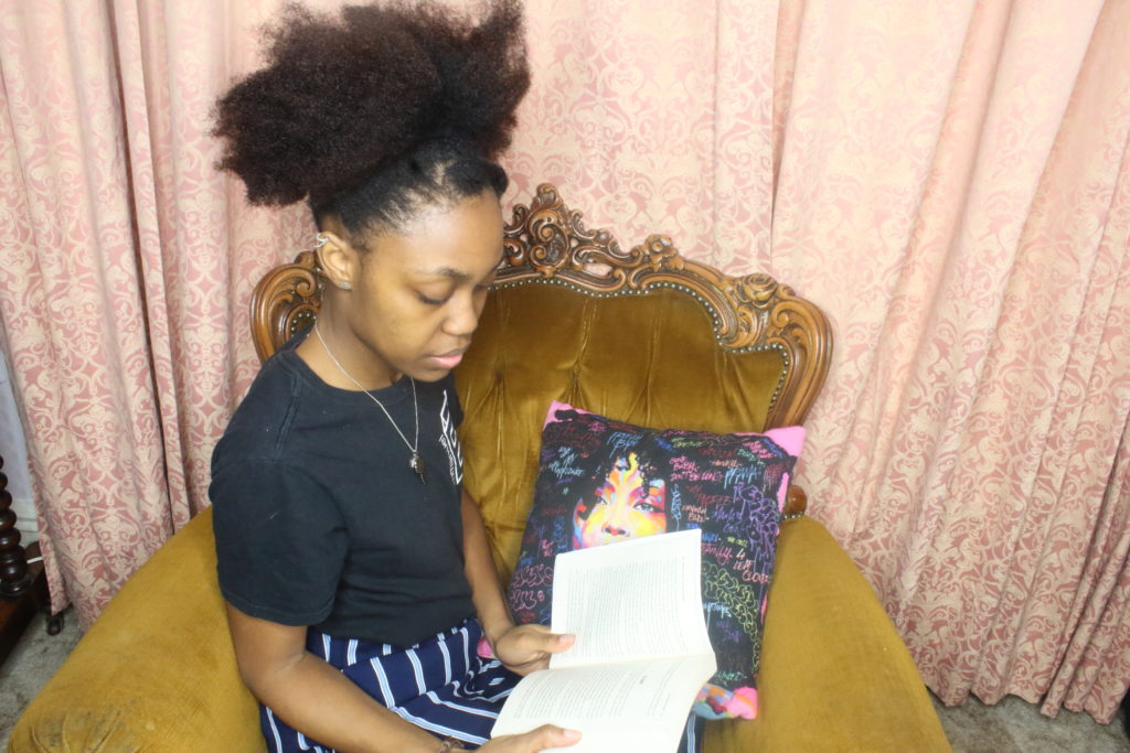 black girl with afro puff reading in chair