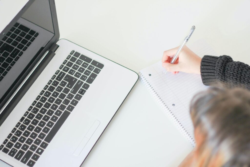 freelance copywriter writing on paper with laptop